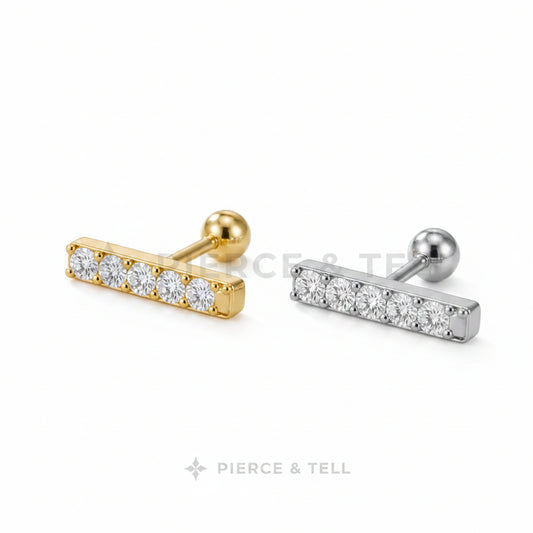 Two gold and silver bar-shaped earrings with clear stones on a light gray background.