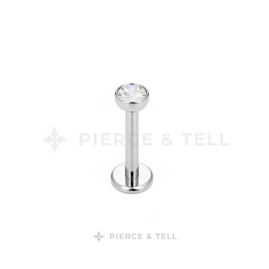 Silver lip ring with a clear gemstone on a white background, branded 'Pierce & Tell'.