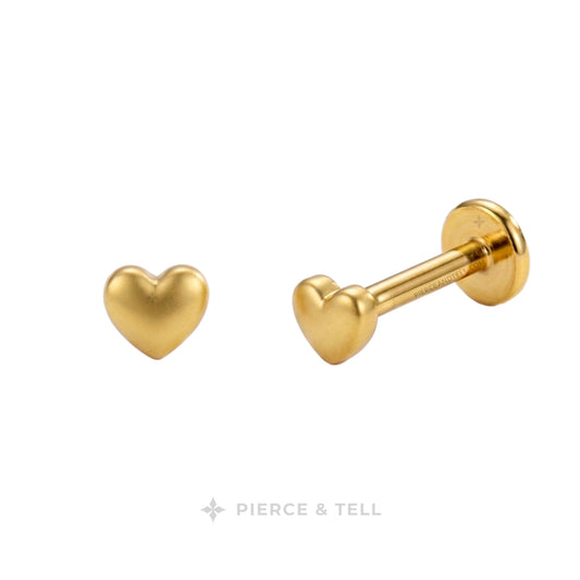 Gold heart-shaped labret stud earrings shown from front and side angles on a white background, with the PIERCE & TELL logo at the bottom.