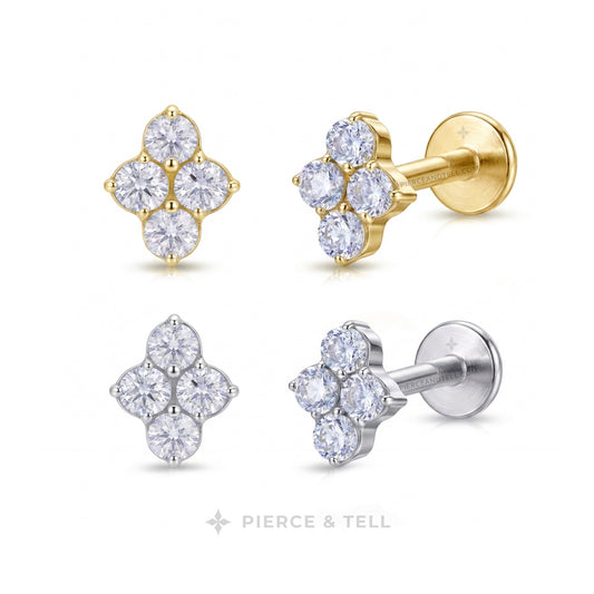 Two flower-shaped stud earrings on a white background, one in yellow gold and one in silver. Each earring has five clear gemstones, with the center of the gold earring filled with a gold bead and the center of the silver earring filled with a silver bead.