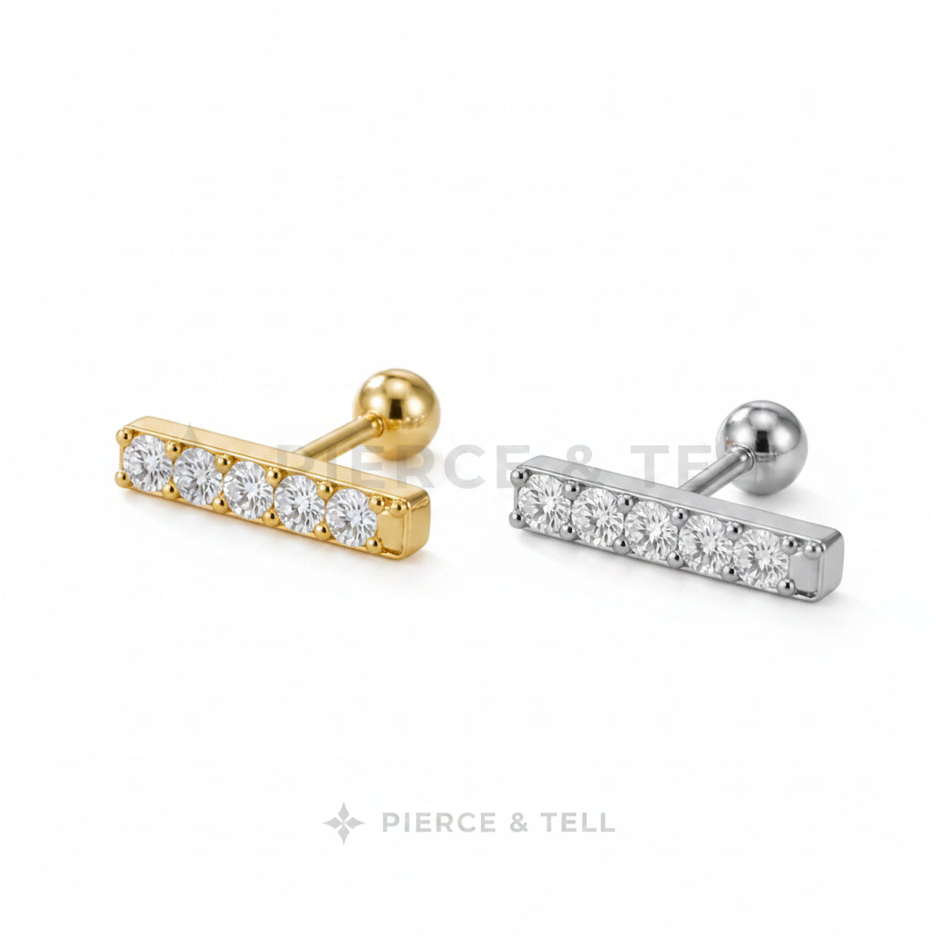 Two gold and silver bar-shaped earrings with clear stones on a light gray background.