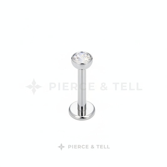 Silver lip ring with a clear gemstone on a white background, branded 'Pierce & Tell'.