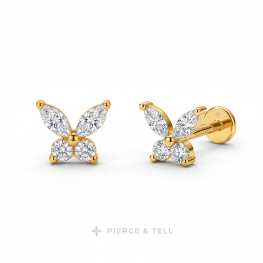 A pair of gold butterfly stud earrings with marquise and round-cut clear gemstones, shown on a white background with the PIERCE & TELL logo below.