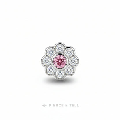 A flower-shaped silver-toned jewelry charm featuring a central round pink gemstone surrounded by a halo of clear cubic zirconia stones, shown on a white background with the PIERCE & TELL logo below.