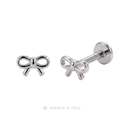 A pair of silver bow stud earrings, one shown from the front and the other from the side/back to display the post and flat back. The brand name 'PIERCE & TELL' is printed at the bottom of the image on a white background.