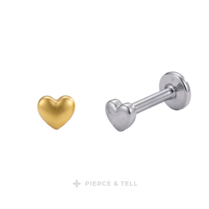 Two heart-shaped labret ear piercings shown on a plain white background: one in polished yellow gold and one in polished silver. The brand name 'PIERCE & TELL' is printed at the bottom.