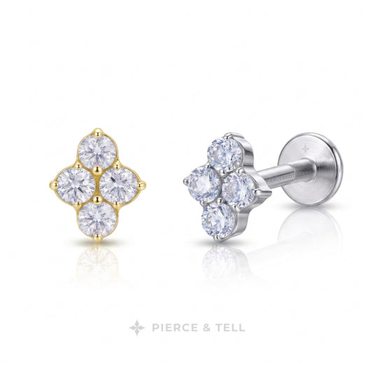 A pair of stud earrings from Pierce & Tell, featuring a yellow gold four-petal cluster with clear round gemstones on the left, and a silver-toned four-petal cluster with clear round gemstones on the right. The earrings are displayed on a clean white background with a soft reflection below.