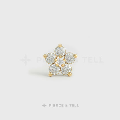 Gold flower earring with clear gemstones on a light gray background