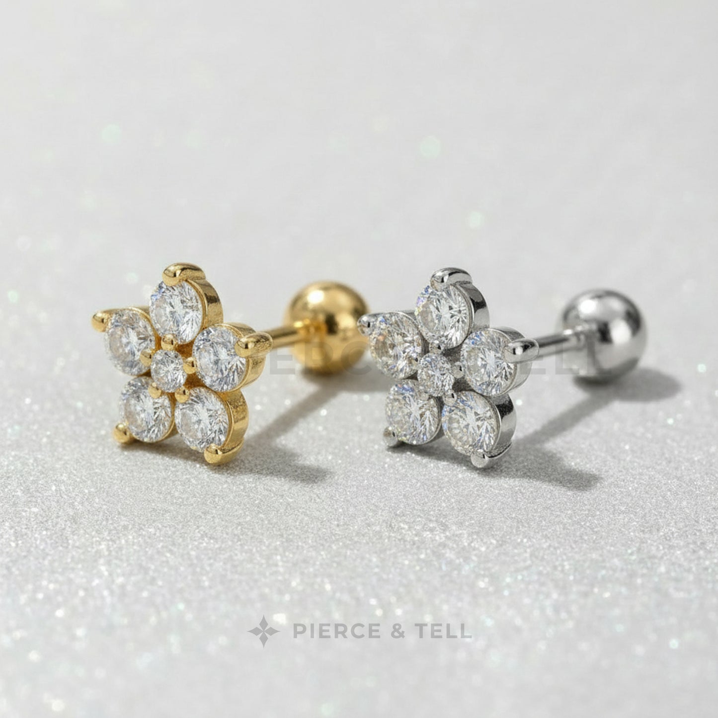 Gold and silver earrings with clear gemstones on a light gray background, branded 'Pierce & Tell'.
