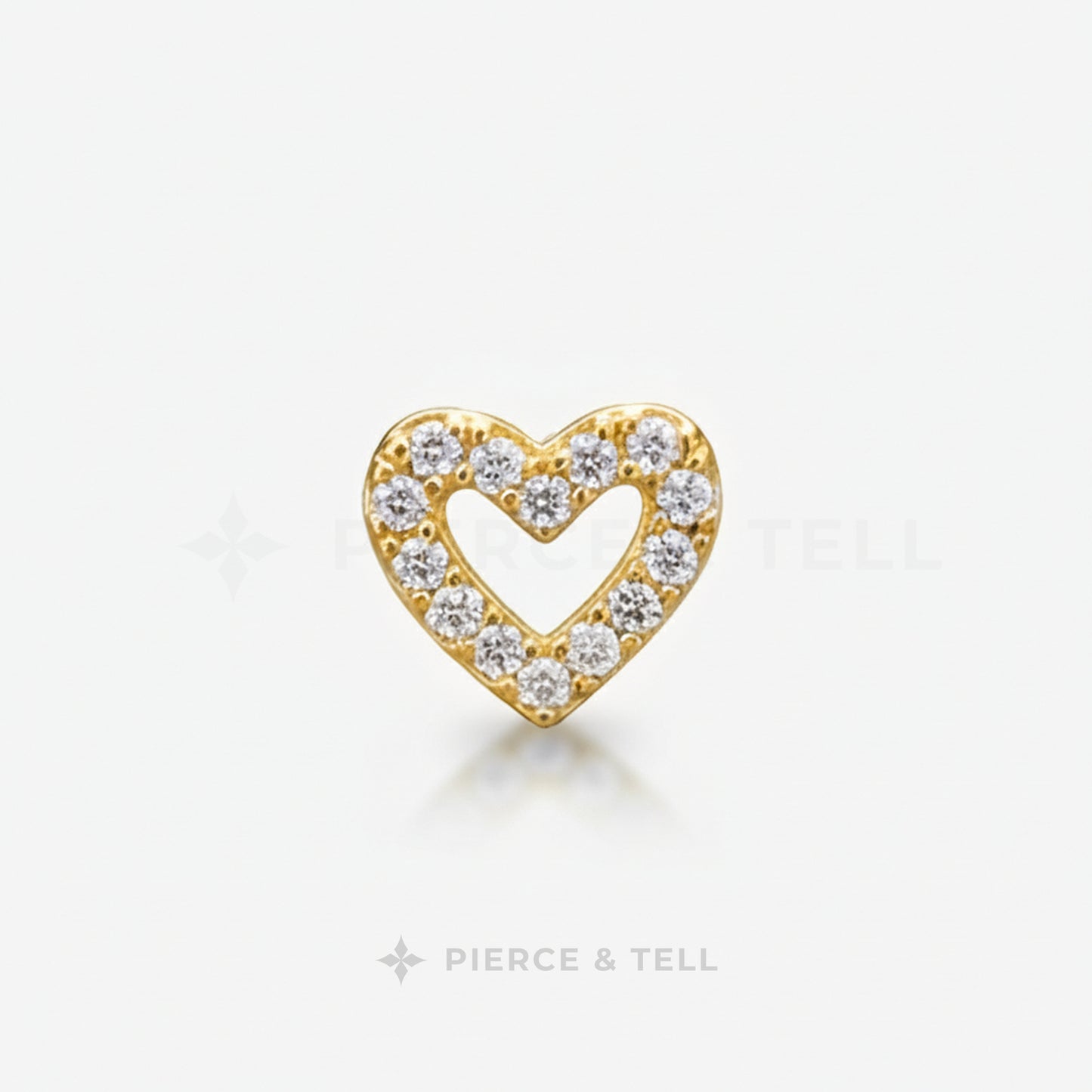 Gold and silver heart-shaped earring with diamonds on a white background, branded 'Pierce & Tell'.