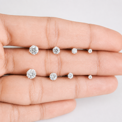 A close-up of a hand displaying a set of silver-toned rings with round-cut clear gemstones in different sizes.