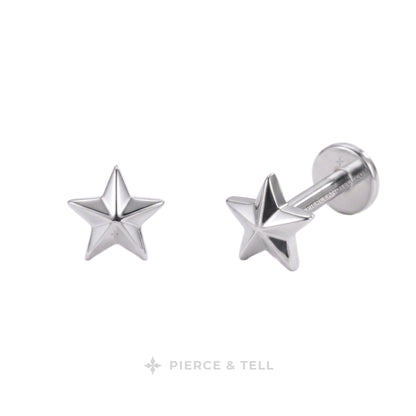 A pair of silver star-shaped labret stud earrings by Pierce & Tell, shown on a clean white background with one earring facing forward and the other angled to show the post and backing.