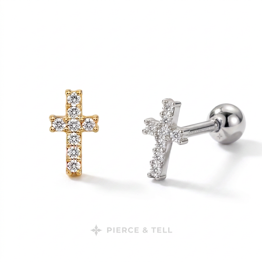 Two cross-shaped stud earrings on a white background, one in yellow gold with clear stones and one in silver with clear stones, with the brand name 'PIERCE & TELL' at the bottom.