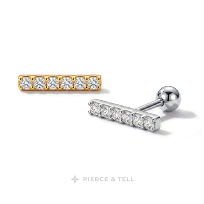 Two bar stud earrings on a white background, one in yellow gold with five clear stones and one in silver with five clear stones, with the PIERCE & TELL logo at the bottom.